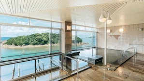 Un vaste espace intérieur doté de grandes fenêtres donnant sur une plage et la mer.