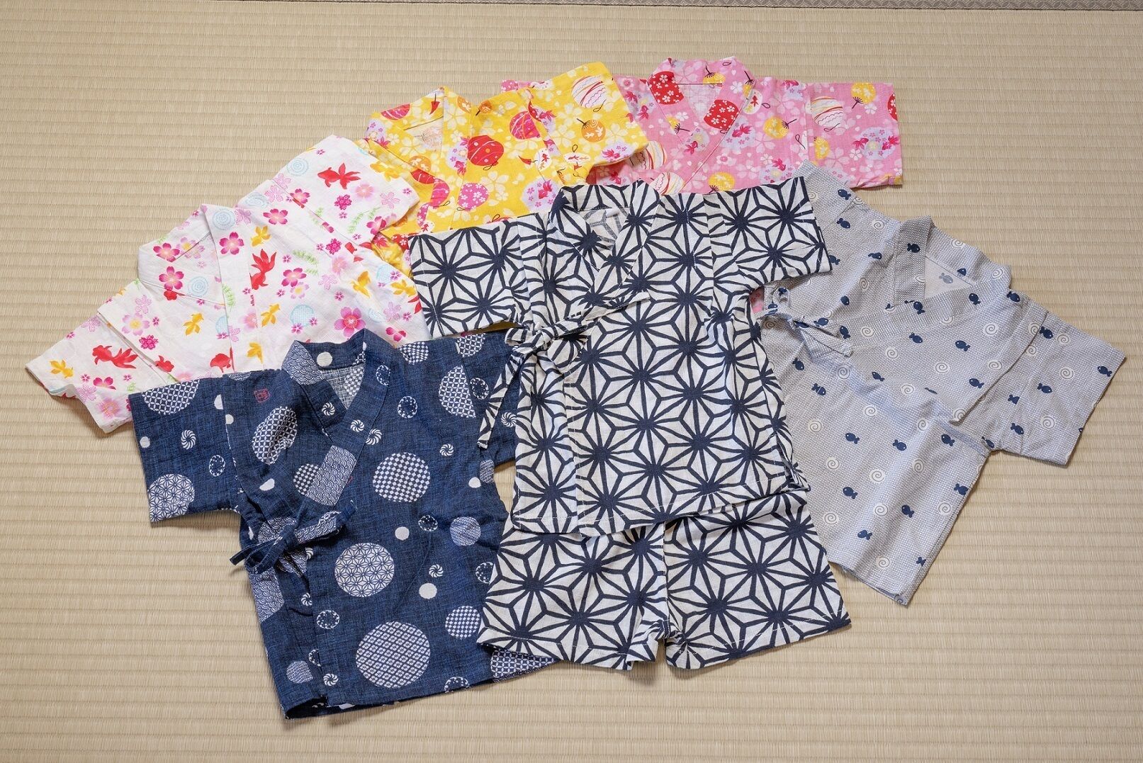Diverse kinderkleding uitgestald op een oppervlak met structuur.