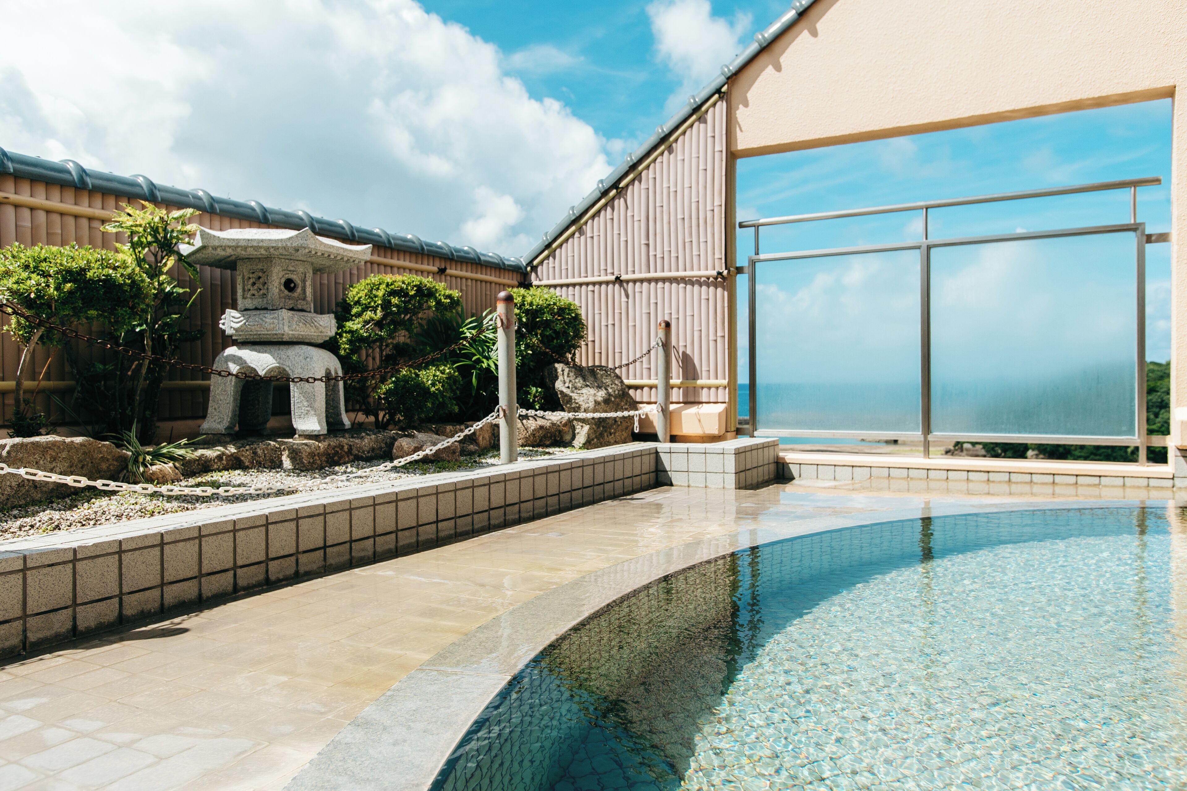 A swimming pool with a stone structure and a view of the sea.