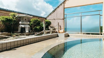 A swimming pool with a stone structure and a view of the sea.