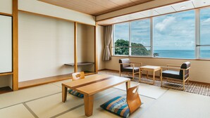Une pièce de style japonais traditionnel, avec un sol recouvert de tatamis, une petite table en bois et une vue sur la mer.
