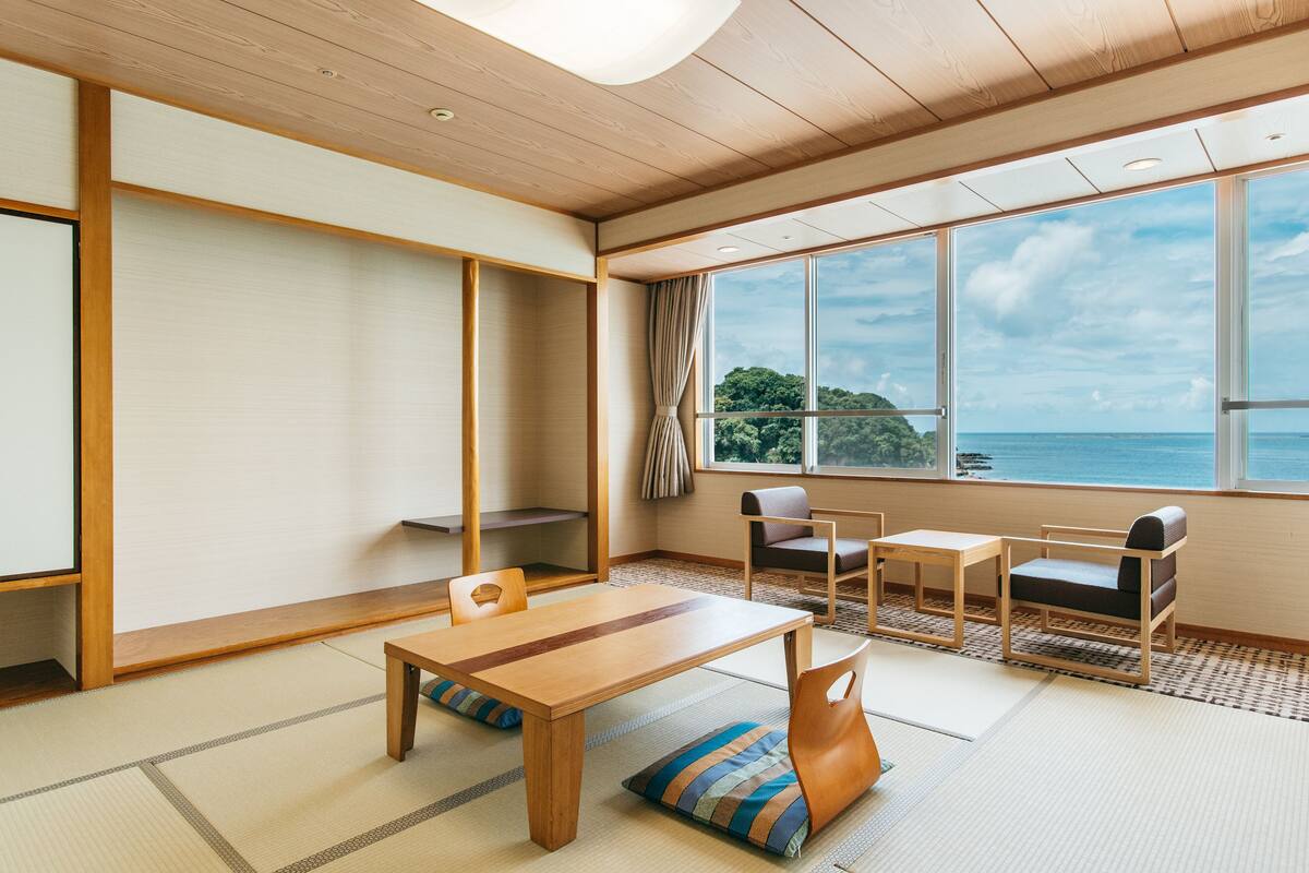 Ein traditioneller japanischer Raum mit Tatami-Boden, einem niedrigen Holztisch und Blick auf das Meer.