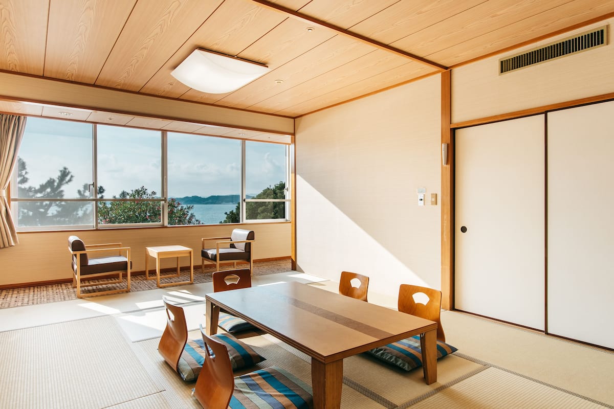 Ein traditioneller japanischer Raum mit Tatami-Böden, einem niedrigen Tisch und verschiebbaren Türen.