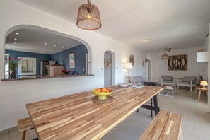 A modern kitchen with a wooden countertop, a bowl of fruit, and a hanging light fixture.