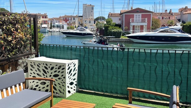 A terrace with wooden furniture, a green artificial lawn, and a view of boats and buildings. - Nice view - PORT GRIMAUD (Grimaud)