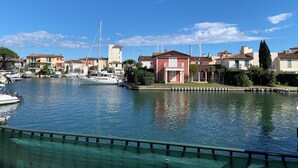 A marina with boats docked, a clear blue sky, and buildings with red and white facades. - Nice view - PORT GRIMAUD (Grimaud)