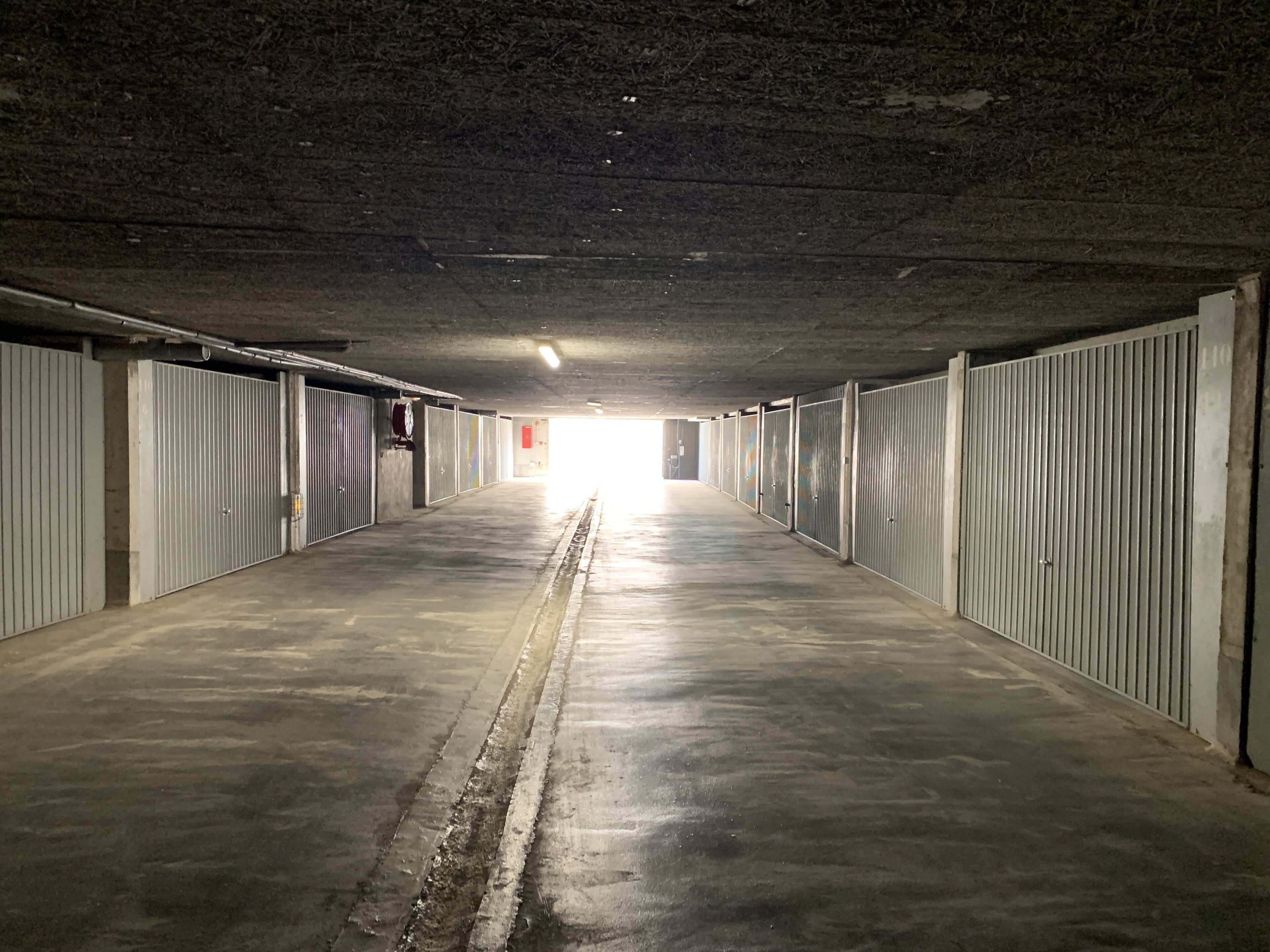 Ein langer, schmaler Korridor mit Metalttüren an beiden Seiten, der zu einem hellen Ausgang am Ende führt.