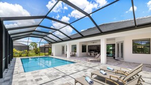 A modern outdoor pool area with a glass ceiling, lounge chairs, and a view of the surrounding landscape.