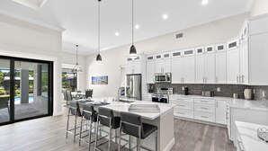 A modern kitchen with white cabinets, stainless steel appliances, and a large island with bar stools.