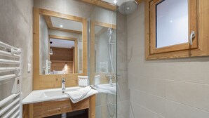 A modern bathroom with a wooden vanity, a glass shower enclosure, and a large mirror.