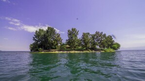 A small island with dense trees and a clear sky. - Paradis Malahide (Nyayumba)