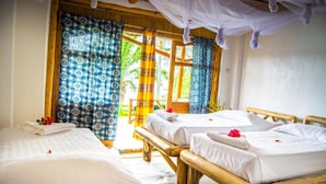 A room with two wooden beds, a large window with patterned curtains, and a canopy bed. - Paradis Malahide (Nyayumba)