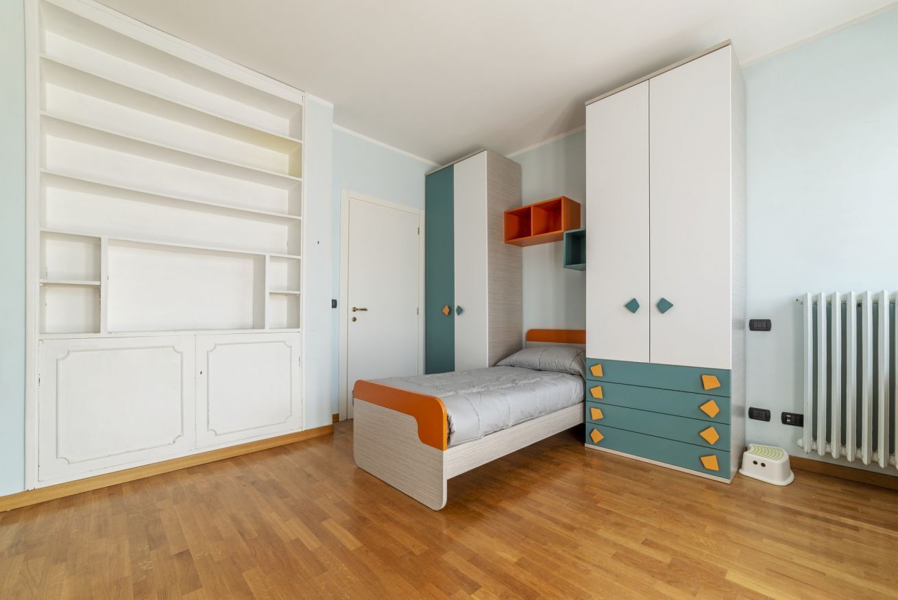 Een slaapkamer met een bed, kast en radiator.