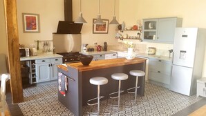Una cocina moderna con una isla central, taburetes de bar, estufa y refrigerador.