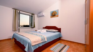 Une chambre à coucher avec un lit, une fenêtre, un climatiseur, un tableau et un plancher en bois.