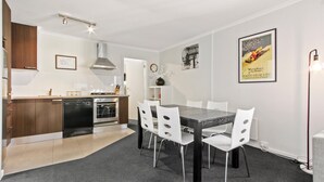 Eine moderne Küche mit Geschirrspüler, Backofen und Essbereich mit Tisch und Stühlen.