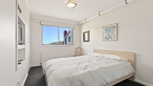Ein Schlafzimmer mit einem Bett, einem Fenster, einer Heizung und einem Sessel.