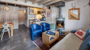 A cozy living room with a fireplace, blue chairs, a wooden coffee table, and a sofa.