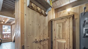 A wooden interior with a wooden door, a small stool, and a control panel.