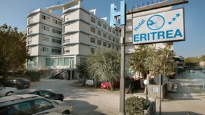 A hotel named ERITREA with a signboard, multiple floors, and a parking area with cars. - Hotel Eritrea (Cesenatico)