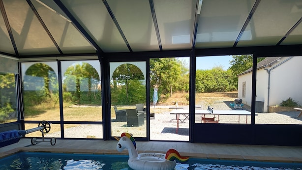 Una piscina con un flotador de cisne, ventanas amplias y mobiliario exterior.