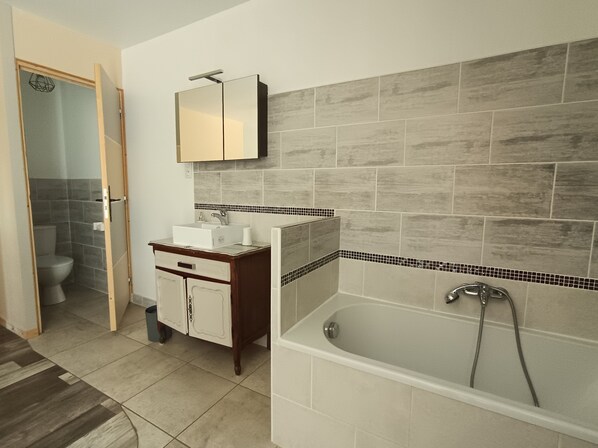 A modern bathroom with a bathtub, a sink, and a toilet.