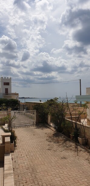 Stroll along the paved walkway to an entrance, surrounded by a coastal landscape.