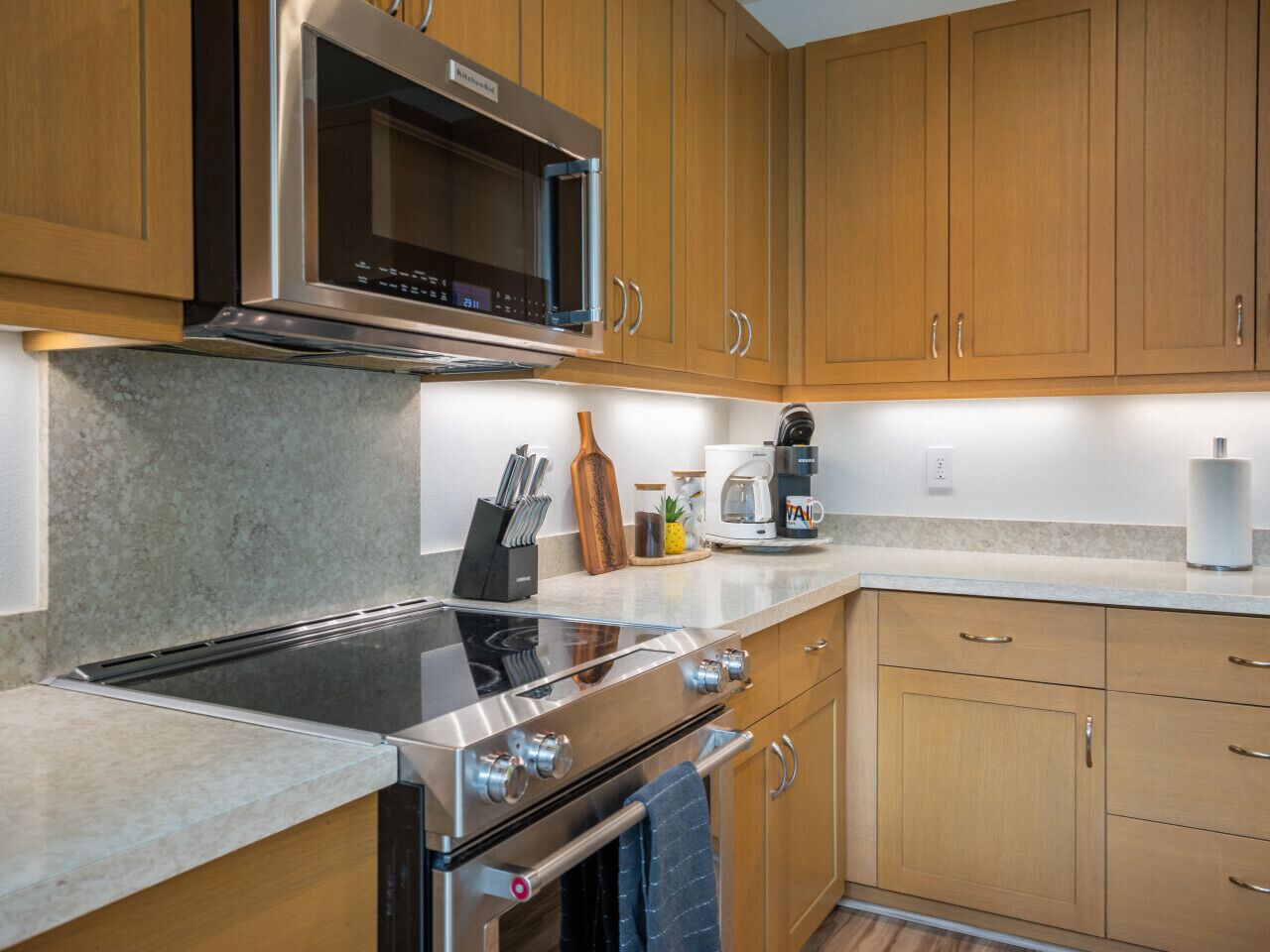 A modern kitchen with stainless steel appliances, wooden cabinets, and a granite countertop.