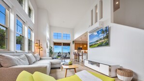 Ein geräumiges Wohnzimmer mit einer Couch, einem Couchtisch und einem an der Wand befestigten Fernseher.