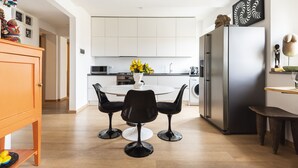 A modern kitchen with white cabinets, a stainless steel refrigerator, and a round dining table with black chairs. - Matteotti Apartment - Two Bedroom Apartment, Sleeps 6 (Firenze)