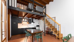 Eine moderne Küche mit Essbereich, ausgestattet mit einer Holztreppe und grünen Stühlen.