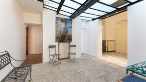 Een ruime binnenruimte met een hoge plafond, een dakraam en een groot schilderij aan de wand.