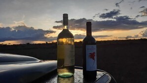 Dos botellas de vino sobre una mesa con el atardecer de fondo.
