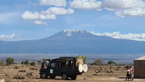 Un vehículo estacionado en un paisaje árido y abierto, con una montaña al fondo.