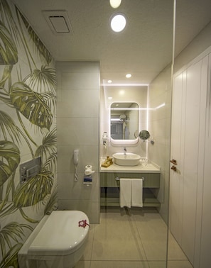 Bathroom features a white toilet, sink, and mirror, with a towel rack and toiletries on a small shelf.