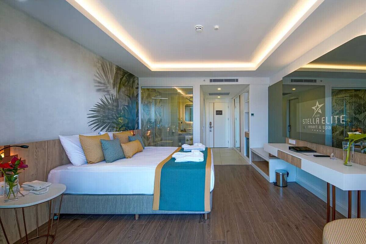A modern hotel room with a bed, bedside table, and a small sitting area.