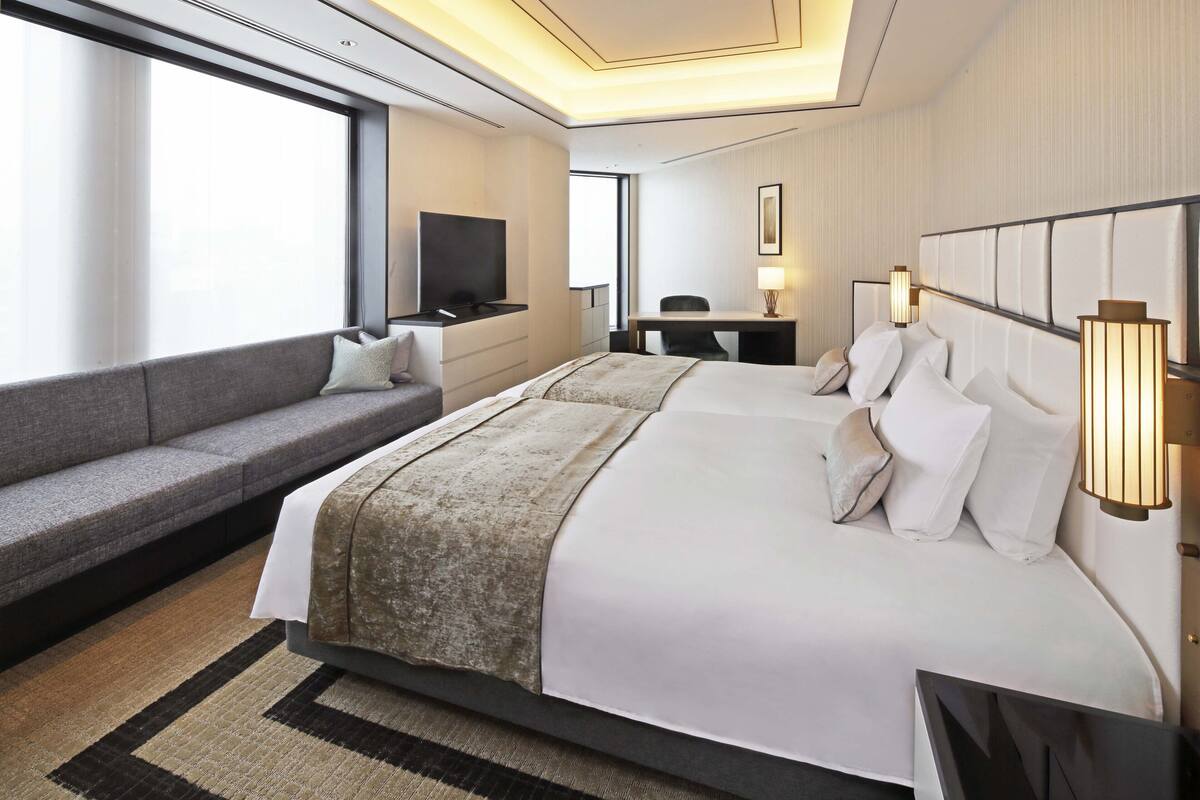 Ett modernt hotellrum med en stor säng, en soffa, ett skrivbord och en TV.
