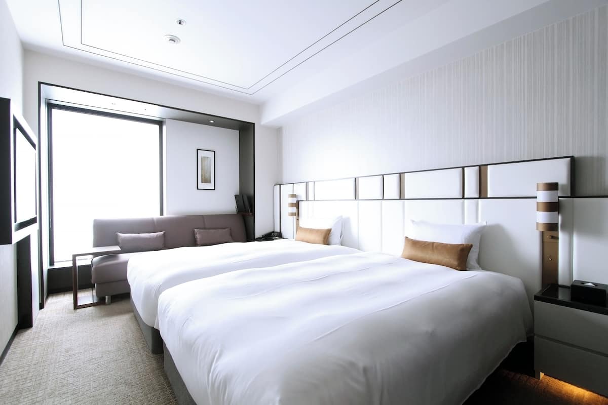 Ett modernt hotellrum med en stor säng, en soffa, ett skrivbord och ett stort fönster.