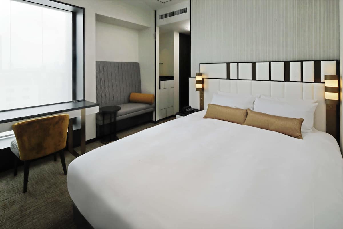 Ett hotellrum med en stor säng, ett skrivbord, en stol och en soffa.