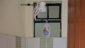 Een badkamer met een douche, toilet en raam.