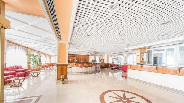 Un amplio vestíbulo con una recepción central, zonas de estar y un diseño decorativo en el suelo.