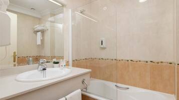 Un baño moderno con ducha envuelta en vidrio, un lavamanos blanco y una bañera.