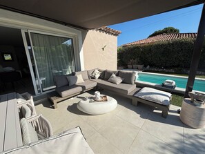 A modern outdoor living area with a sofa set, a coffee table, and a poolside view.