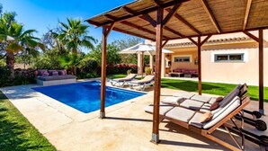 Ein Poolbereich mit Liegestühlen und einer Pergola.