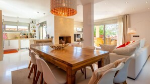 Eine moderne Küche mit Essbereich, weißen Möbeln und einem großen Holztisch.