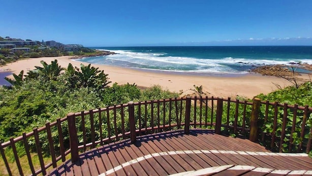 A wooden deck overlooking a beach with ocean waves, surrounded by greenery and buildings in the background. - Crayfish Inn No.8 (Margate)