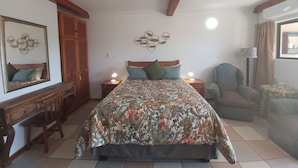 A bedroom with a bed, two bedside tables, a chair, a wooden desk, a mirror, and a window with curtains. - Crayfish Inn No.8 (Margate)