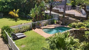 A backyard with a swimming pool, surrounded by a white fence and lush greenery. - Crayfish Inn No.8 (Margate)