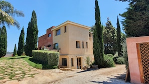A two-story building with a stone facade, a paved driveway, and a well-maintained garden with cypress trees. - Villa Dammusello with Pool, Garden & Wi-Fi (Marsala)