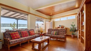 A spacious living room with two patterned sofas, a wooden coffee table, and a bookshelf. - Holiday Home "Villa Mar" close to the Beach with Sea View, Pool & Wi-Fi (Teguise)